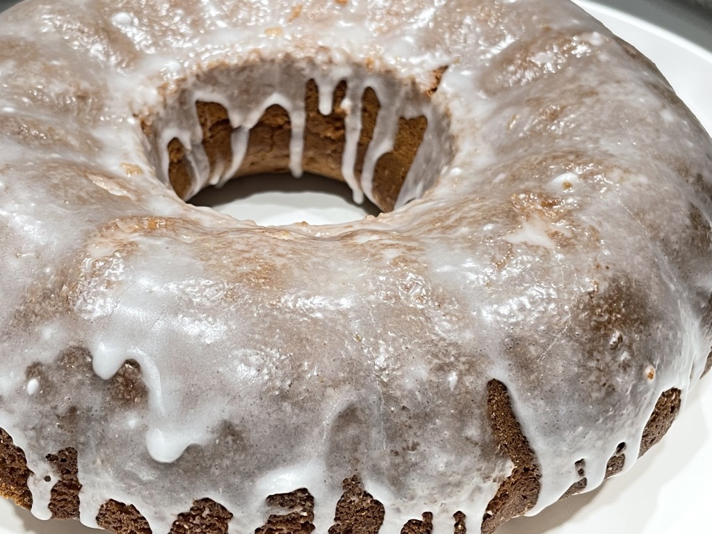 Close up shot of white iced bundt cake on white tray