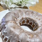 Rustic homemade lemon drizzle cake next to white flowers