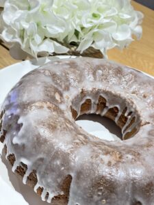 Rustic homemade lemon drizzle cake next to white flowers