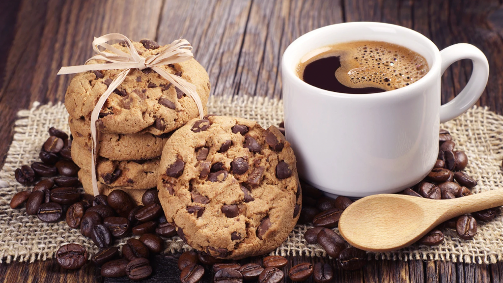 Cup of coffee and chocolate chip cookies with coffee beans and wooden spoon