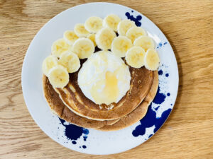 Plate of fluffy sourdough pancakes topped with yoghurt, honey and banana slices