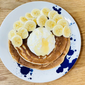 Plate of fluffy sourdough pancakes topped with yoghurt, honey and banana slices