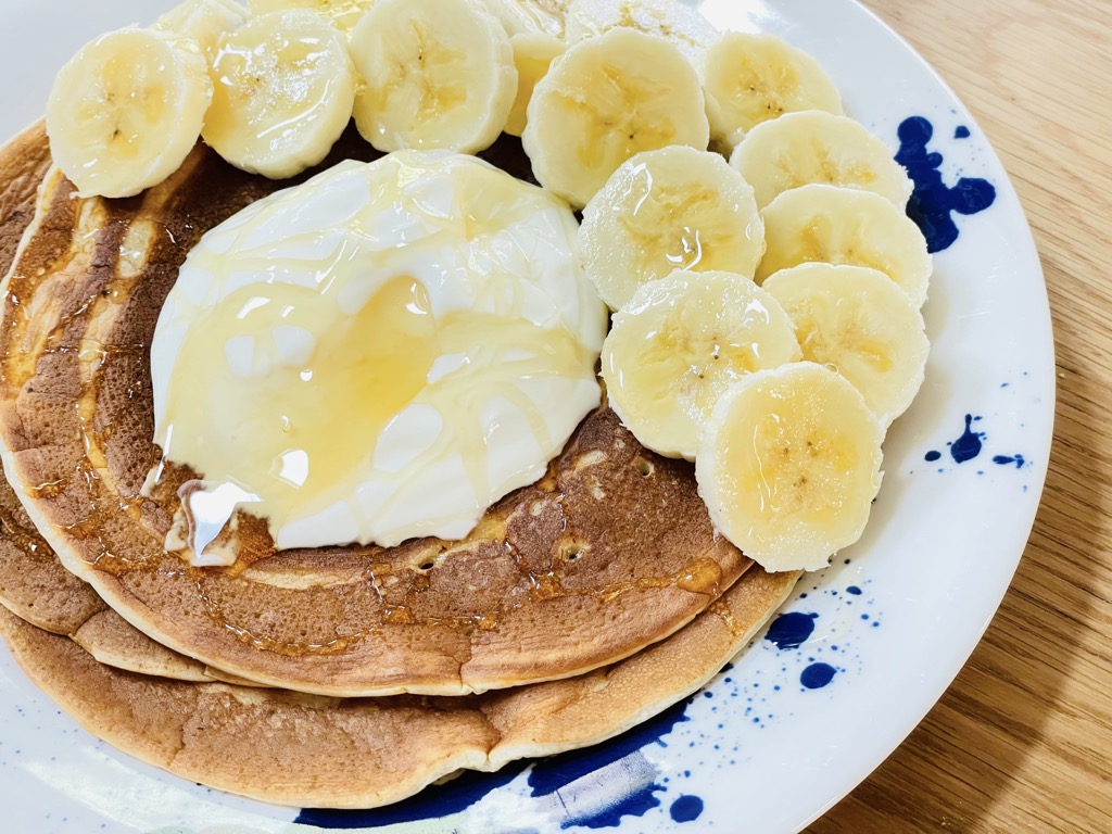 Plate of fluffy sourdough pancakes topped with yoghurt, honey and banana slices