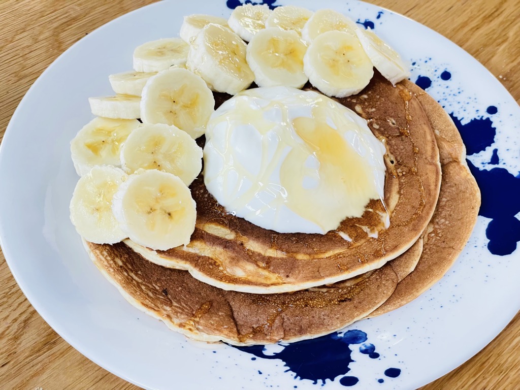 Plate of fluffy sourdough pancakes topped with yoghurt, honey and banana slices