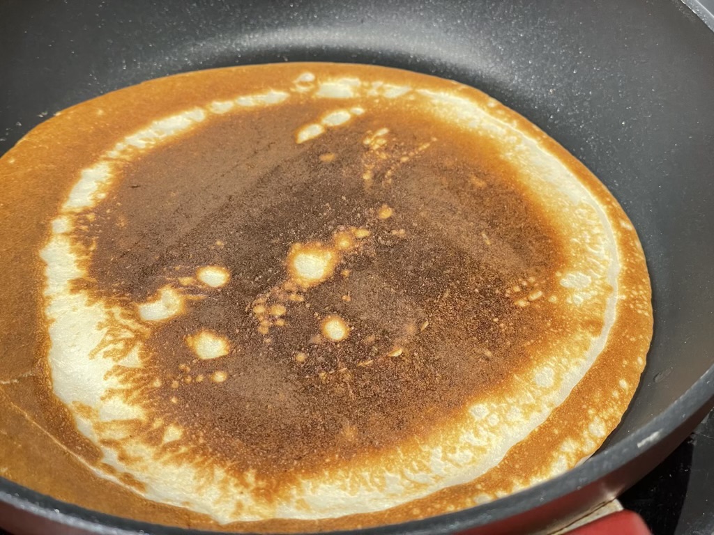 Gluten free pancake baking in black pan