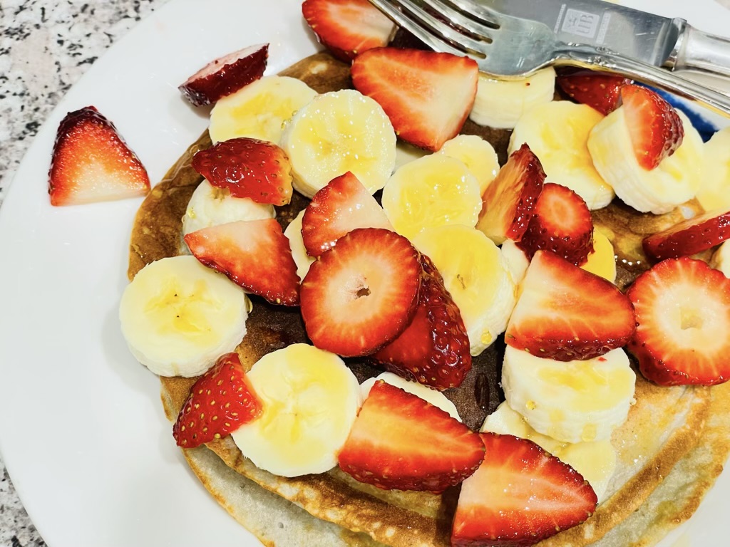 Plate of pancakes topped with strawberries and banana slices