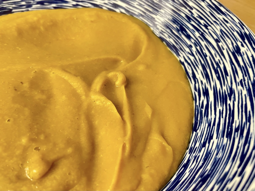 Close up shot of High protein spiced sweet potato soup with legumes in soup bowl