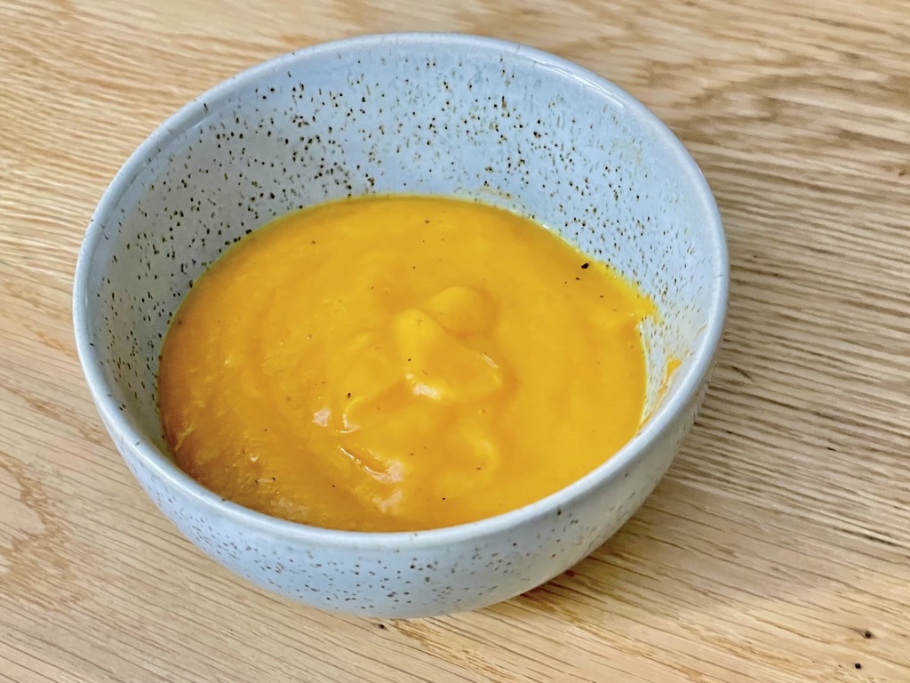 Duck egg bowl of High protein spiced sweet potato soup with legumes on wooden table