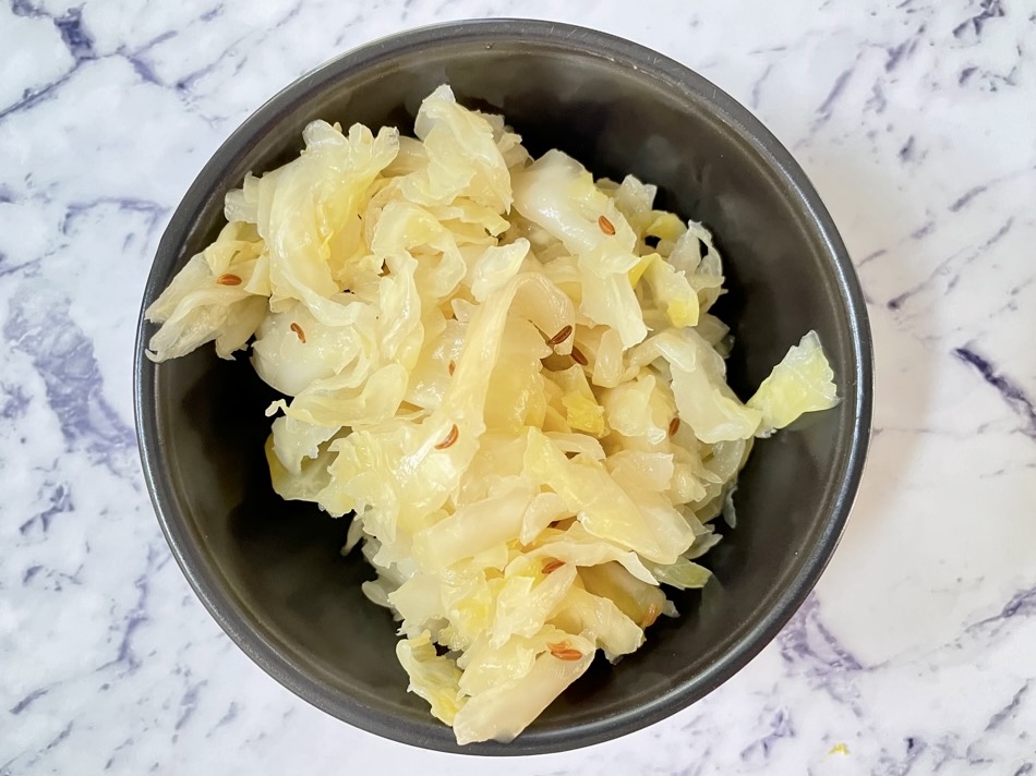 Probiotic-rich fermented cabbage with caraway seeds in black bowl