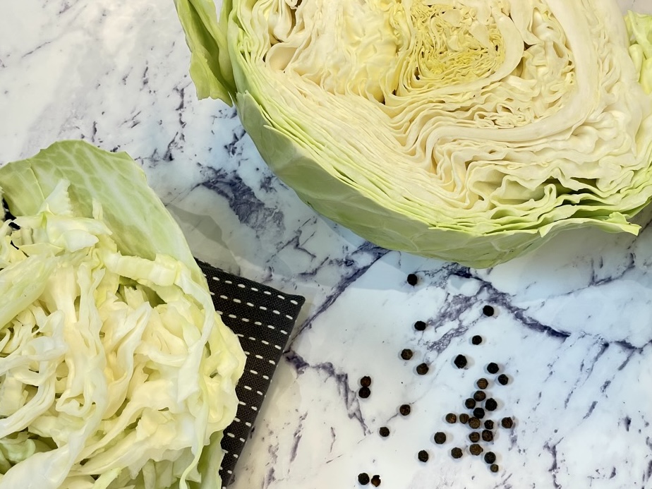 half head of white cabbage with pepper corns on bench