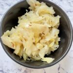 Probiotic-rich fermented cabbage with caraway seeds (Traditional German Sauerkraut) in black bowl