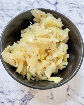 Probiotic-rich fermented cabbage with caraway seeds (Traditional German Sauerkraut) in black bowl