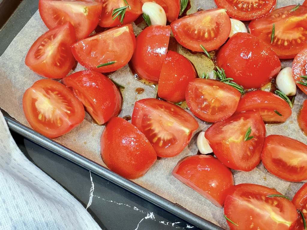 Close up shot of quartered tomatoes and garlic on baking tray