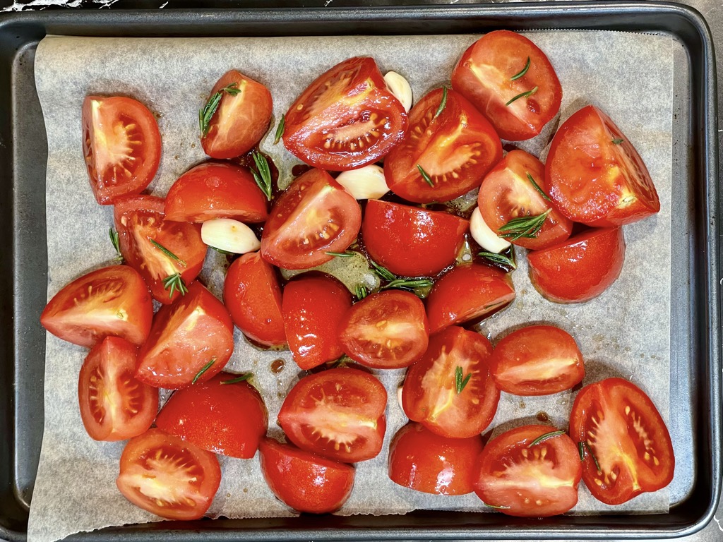 Tray of quartered tomatoes with garlic cloves