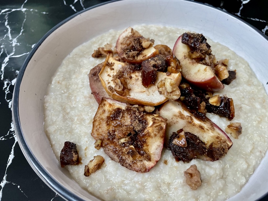 Warming bratapfel porridge in cream bowl on black marble bench