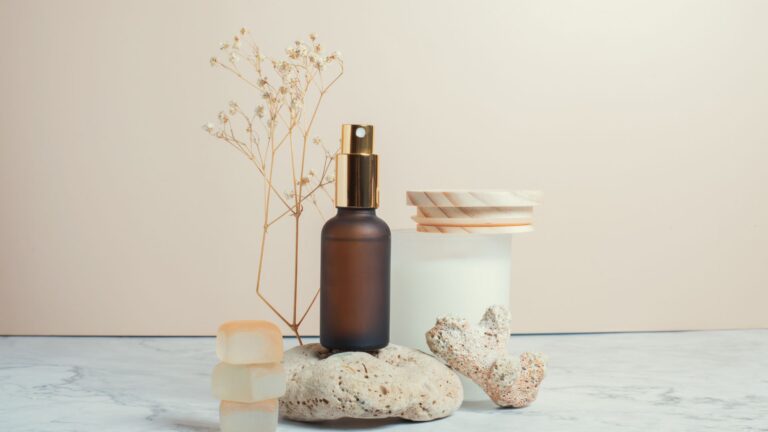 Brown glass spray bottle standing on stone next to glass jar