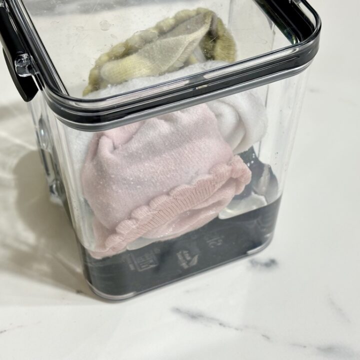 Clear container filled with rolled up socks submerged in liquid