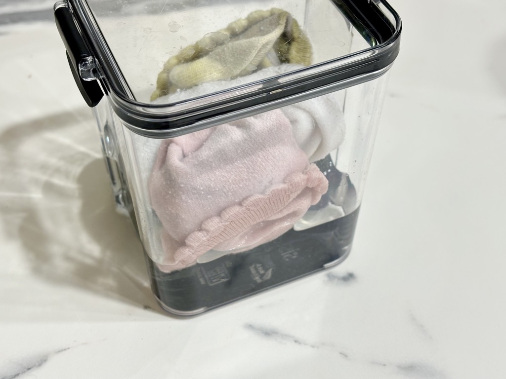 Clear container filled with rolled up socks submerged in liquid