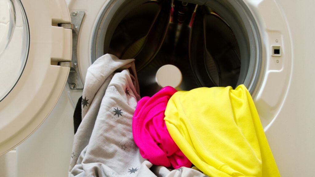 Open clothes dryer with pieces of clothing hanging out