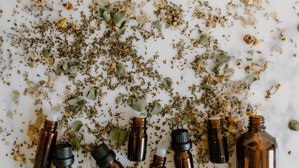 Brown diffuser glass bottles surrounded by dried herbs