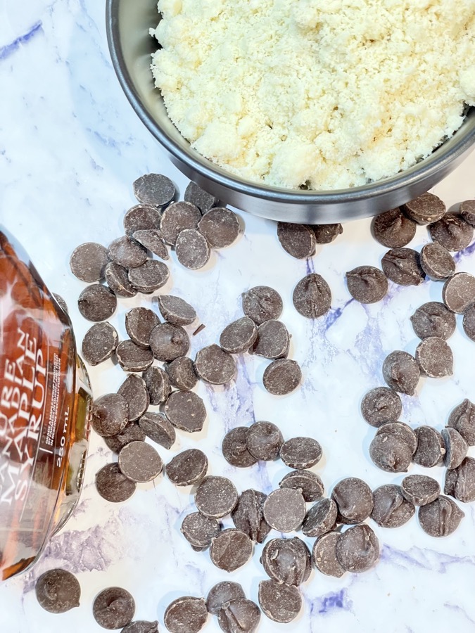 Dark chocolate chips, maple syrup and almond meal on kitchen bench