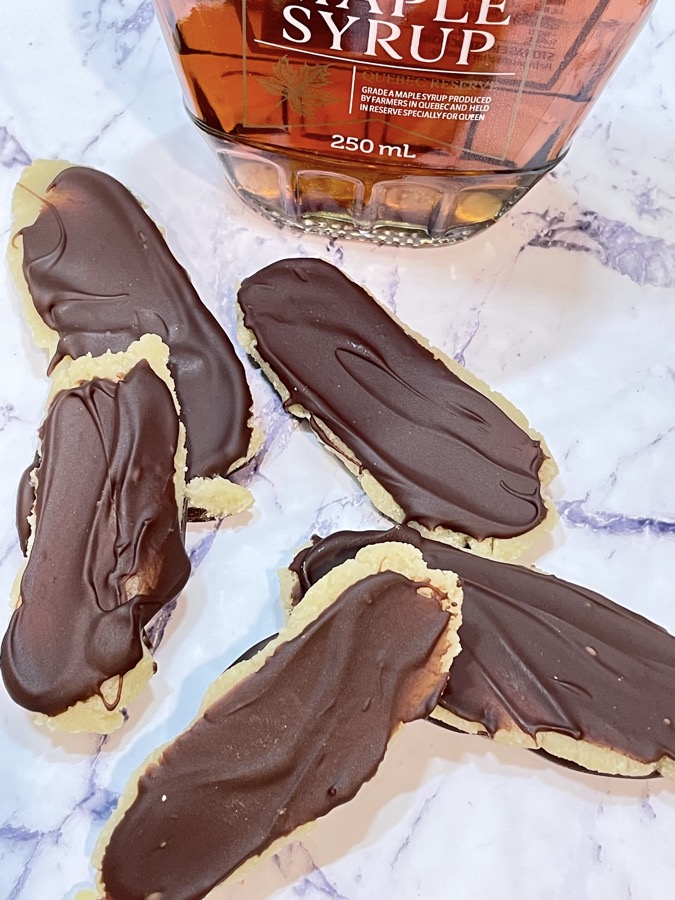 Marzipan filled chocolate bars in front of bottle of maple syrup