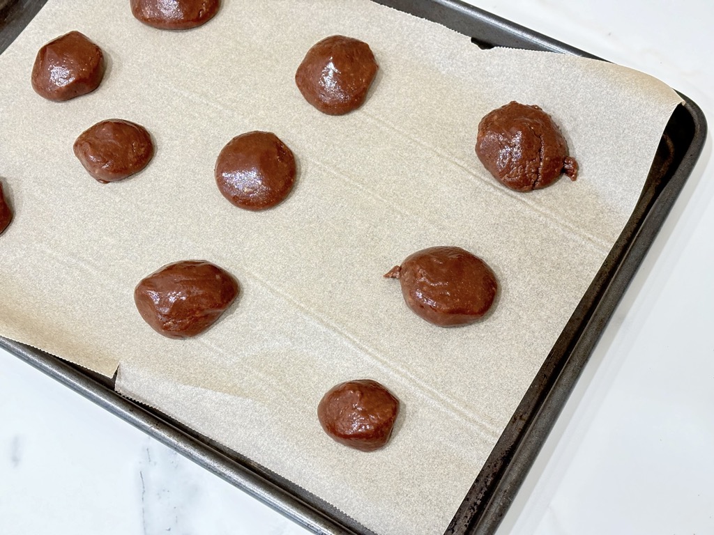 Raw balls of biscuit dough on tray lined with parchment paper