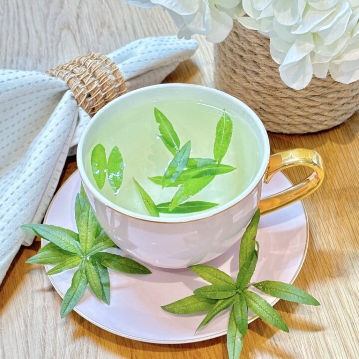 Cup of lemon verbena tea with leaves floating on top and placed on saucer