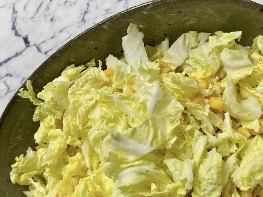 Bowl of Napa cabbage salad with corn and dressing