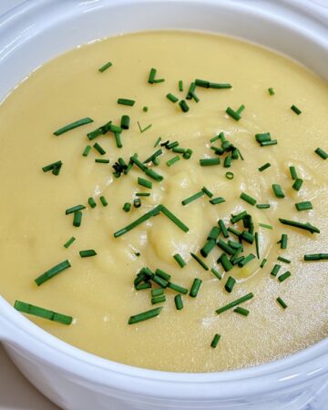 White soup bowl filled with creamy potato soup topped with chives