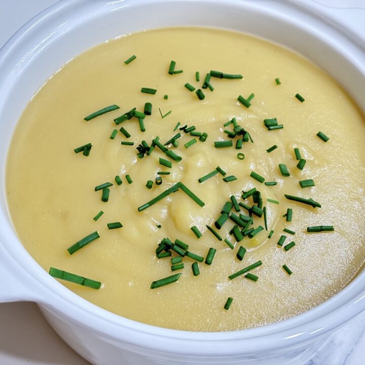 White soup bowl filled with creamy potato soup topped with chives