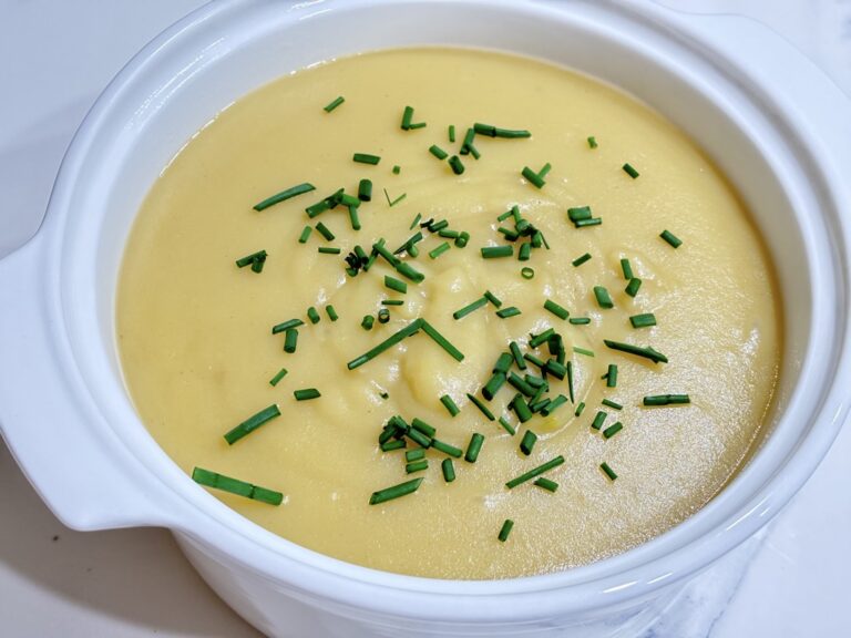 White soup bowl filled with creamy potato soup topped with chives