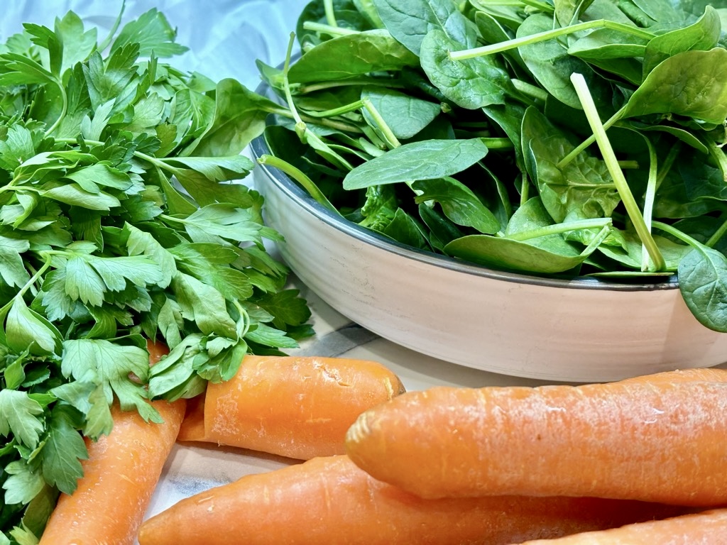 Bowl of baby spinach, bunch of parsley and carrots