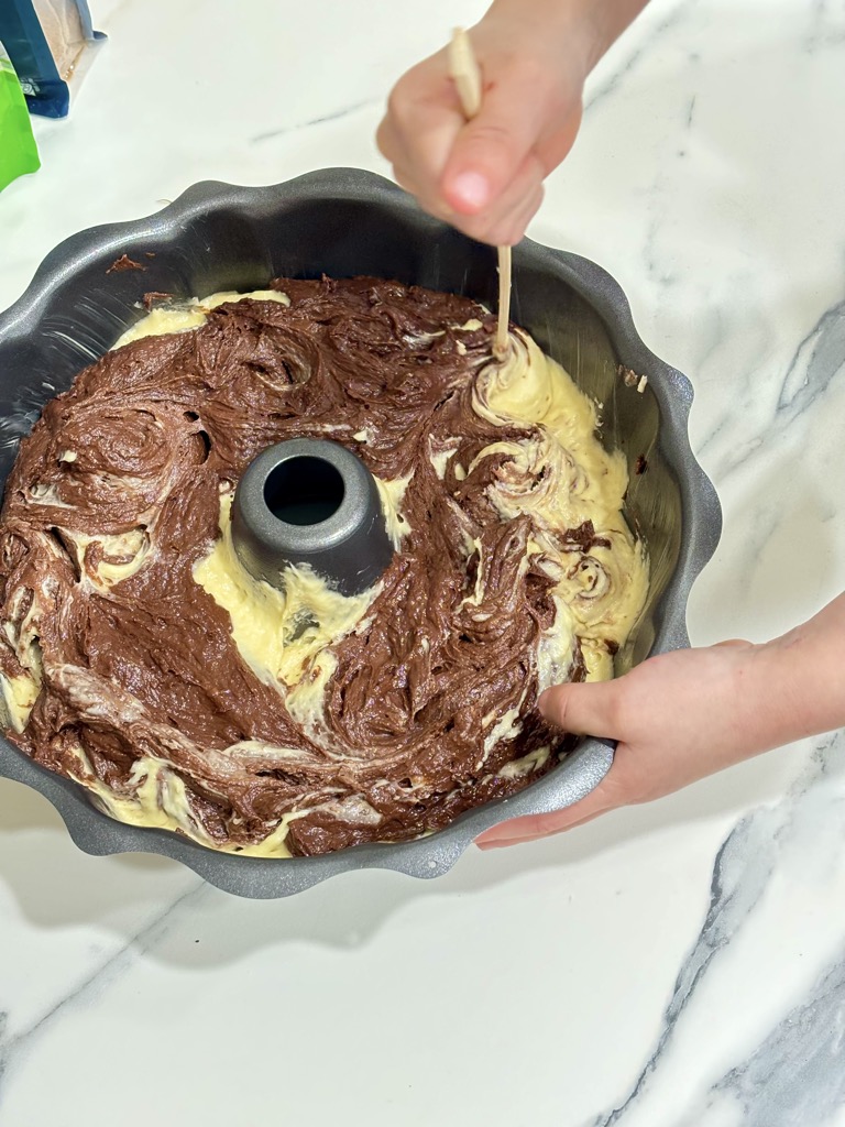 Hand mixing white and brown cake batter in bundt tin