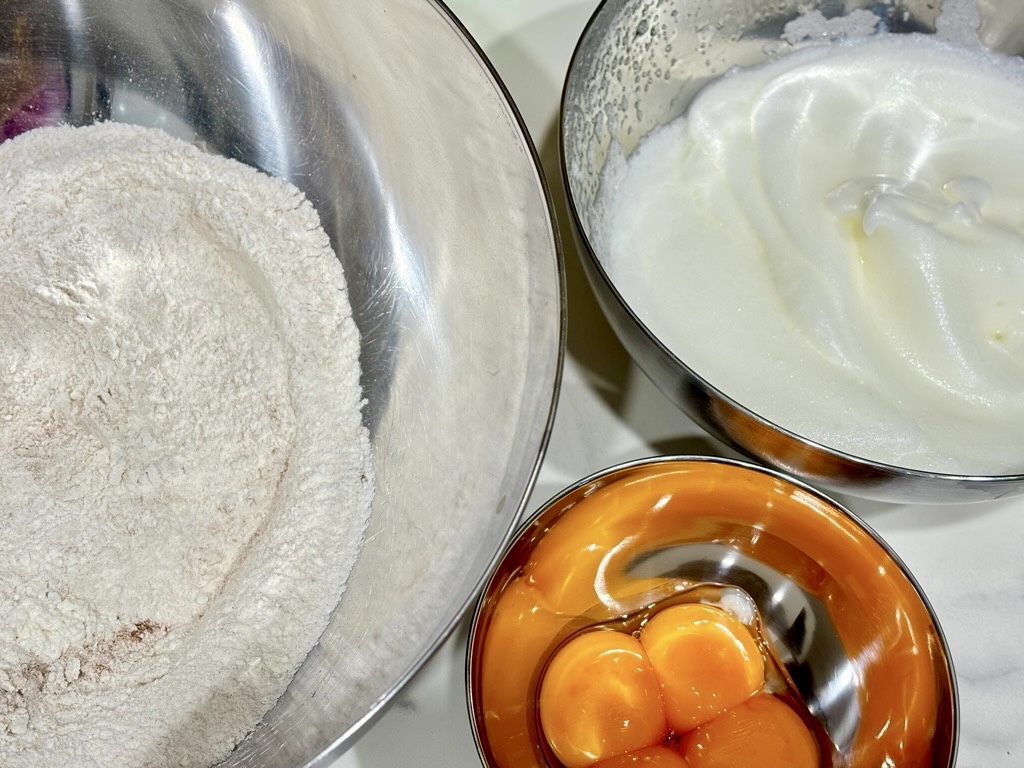 Three silver bowls, one filled with flour, another with egg yolks, the third with beaten egg whites