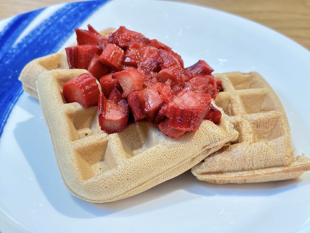 Three waffles on white plate, topped with stewed rhubarb