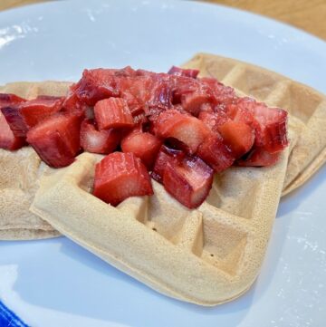 Three waffles on white plate, topped with stewed rhubarb