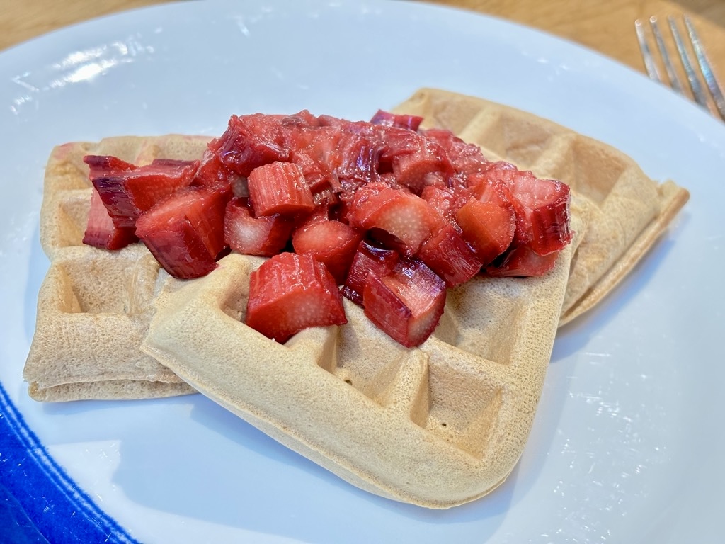 Three waffles on white plate, topped with stewed rhubarb