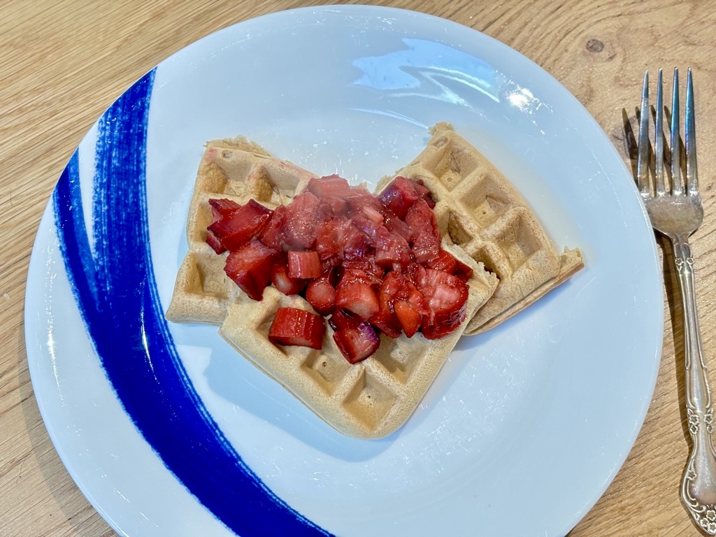 Three waffles on white plate, topped with stewed rhubarb