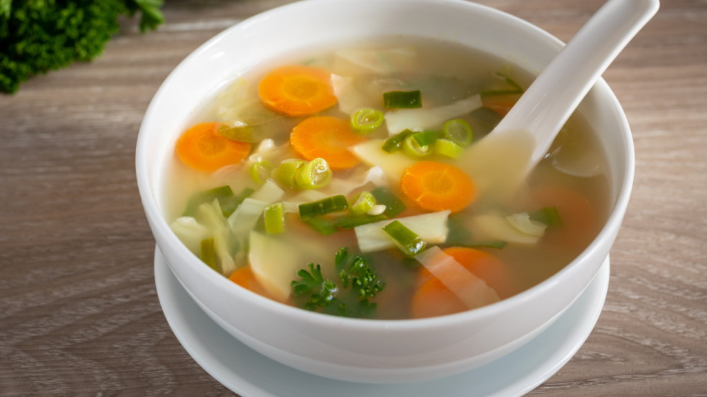 homemade vegetable broth and vegetable slices in white bowl