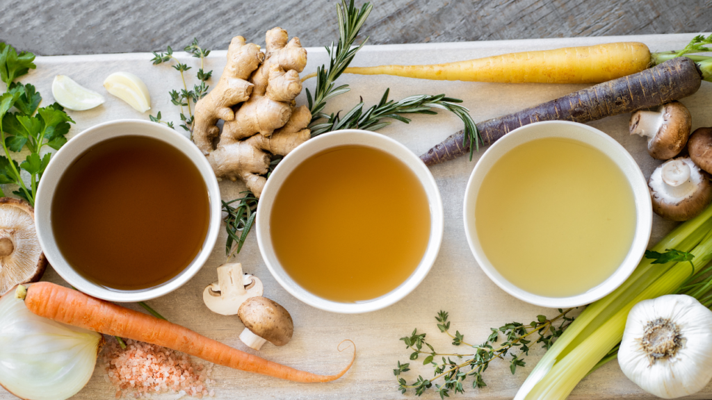 3 bowls of homemade vegetable broth set out on chopping board