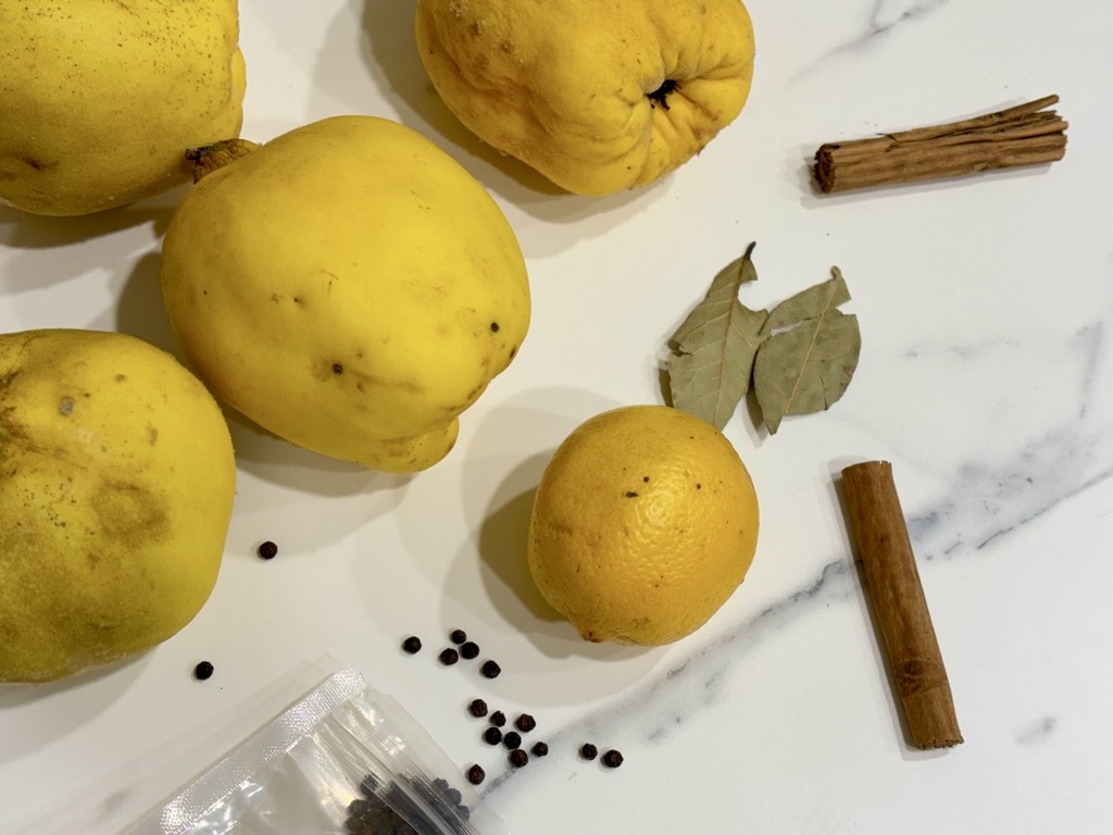 Quinces, lemon and dried spices on marble surface