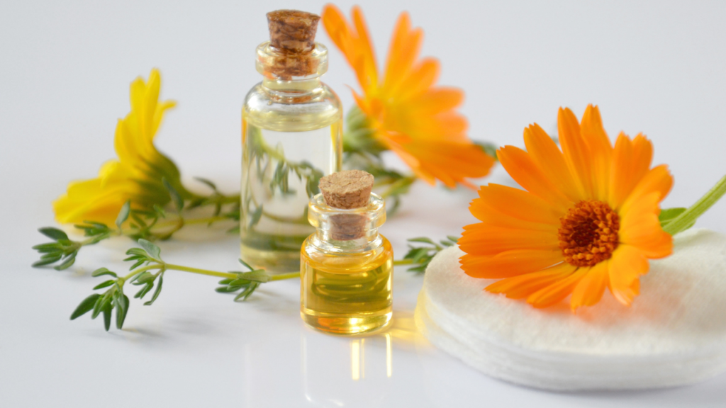 yellow and orange flowers surrounding two small glass bottles of essential oil