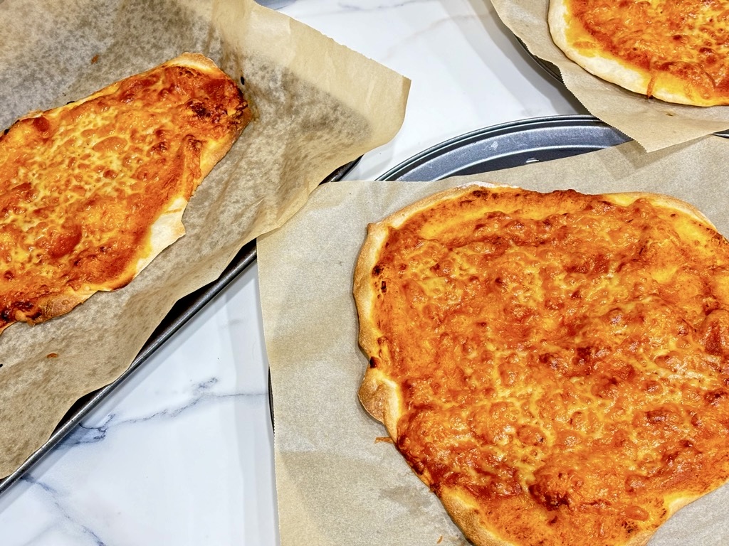 three margarita pizzas on baking sheets