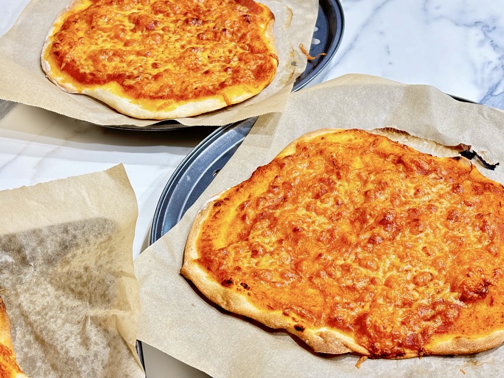 two margarita pizzas on baking sheets