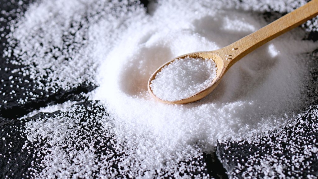 Wooden spoon filled with salt in stash of salt on black surface