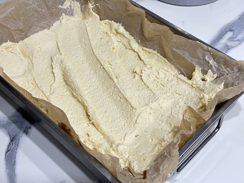 Parchment paper lined silver baking tray filled with raw dough