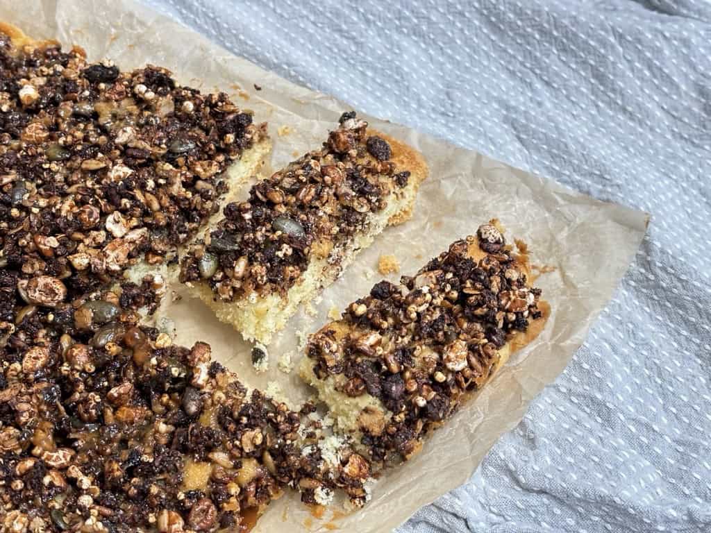 Block of baked granola over batter with two cut slices of granola bars