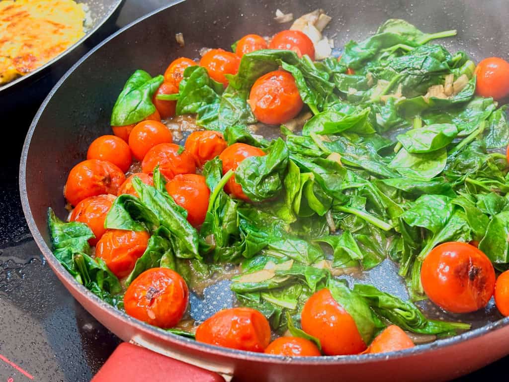 large red pan with baby spinach and cherry tomatoes