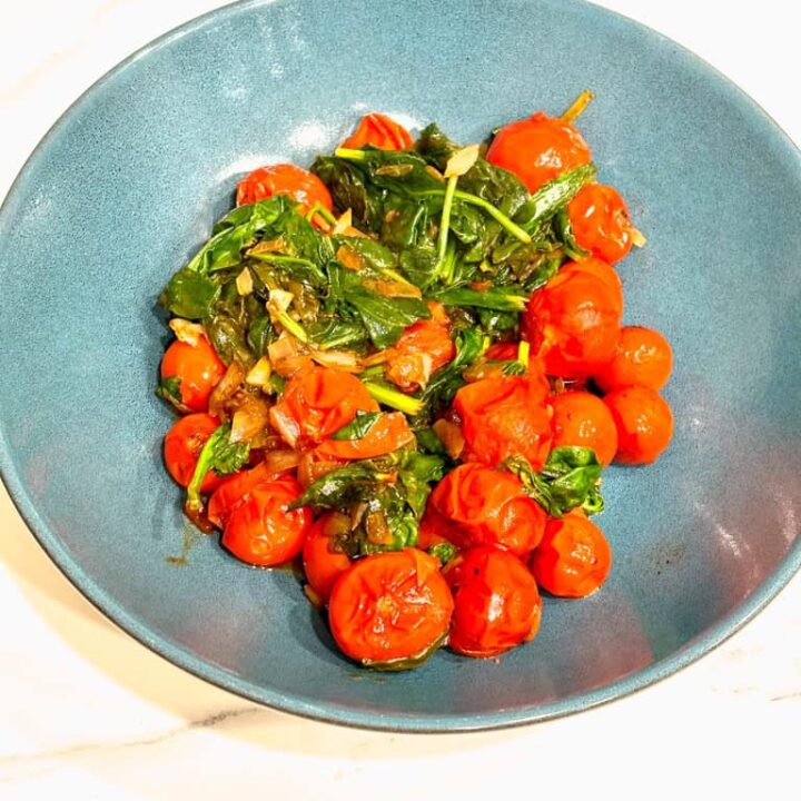 tomato and spinach saute in blue serving bowl